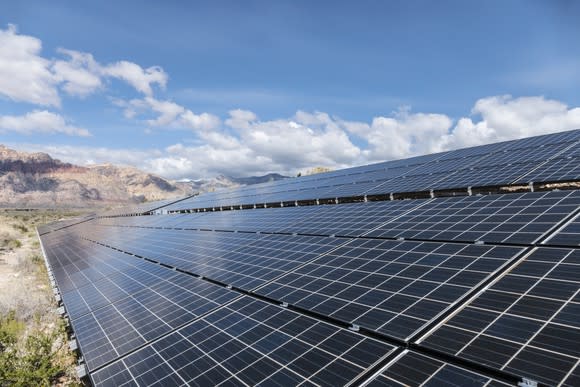 Large solar installation with mountains in the background.