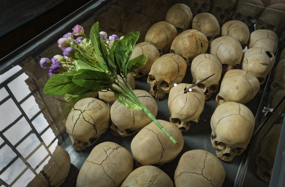 Flowers are laid on top of a glass case containing the skulls of some of those who were slaughtered as they sought refuge in the church, kept as a memorial to the thousands who were killed in and around the Catholic church during the 1994 genocide, inside the church in Ntarama, Rwanda Friday, April 5, 2019. Rwanda will commemorate on Sunday, April 7, 2019 the 25th anniversary of when the country descended into an orgy of violence in which some 800,000 Tutsis and moderate Hutus were massacred by the majority Hutu population over a 100-day period in what was the worst genocide in recent history. (AP Photo/Ben Curtis)