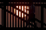 A man looks a his cell phone while crossing a bridge as a hazy sun sets over Century Park in Vernon Hills, Ill., Tuesday, Sept. 15, 2020. The smoke from dozens of wildfires in the western United States has now blanket much of the county along with parts of Mexico and Canada, as residents thousands of miles away on the East Coast are being treated to unusually hazy skies and remarkable sunsets. (John Starks/Daily Herald via AP)