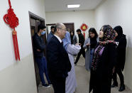 A Chinese teacher, center left, speaks with a student outside a classroom in the Chinese language department at Salahaddin University in Irbil, Iraq, Wednesday, Jan. 19, 2021. The Chinese language school in northern Iraq is attracting students who hope to land jobs with a growing number of Chinese companies in the oil, infrastructure, construction, and telecommunications sectors in the region. (AP Photo/Khalid Mohammed)