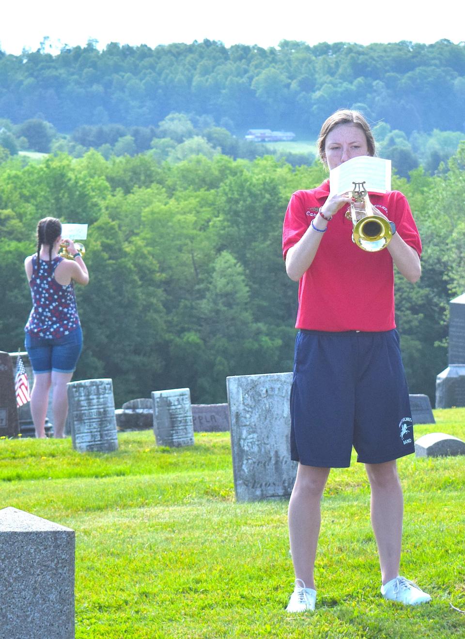 Carolyn Miller (right) and her sister Rosanna (back left) play taps at the Memorial Day ceremony Monday at Oak Hill Cemetery in Millersburg.