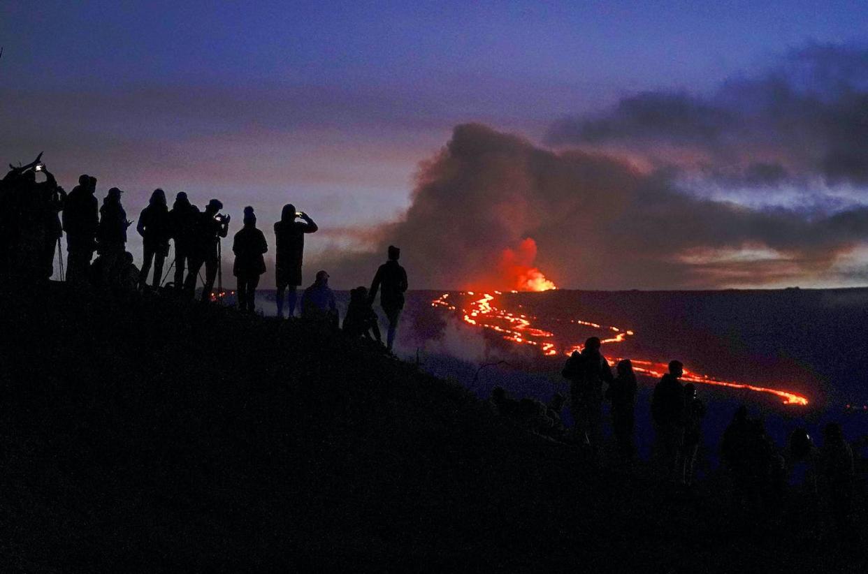 People watch and record images of lava from the Mauna Loa volcano on Dec. 1, 2022 near Hilo, Hawaii. (AP Photo/Gregory Bull)