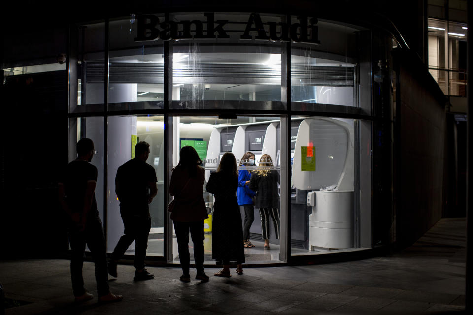 Clients wait to use ATM machines outside a closed bank in Beirut, Lebanon, Wednesday, June 2, 2021. In a reflection of the growing turmoil, scores of Lebanese depositors queued at ATM machines late Wednesday following a decision by the Central Bank that suspended an earlier decree allowing them to withdraw dollars stuck at the bank at a rate two and a half times better than the fixed exchange rate. (AP Photo/Hassan Ammar)