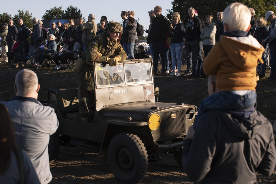 Spectators watch a parade of historic WWII military vehicles prior to a mass parachute drop at Ginkel Heath, eastern Netherlands, Saturday, Sept. 21, 2019, as part of commemorations marking the 75th anniversary of Operation Market Garden, an ultimately unsuccessful airborne and land offensive that Allied leaders hoped would bring a swift end to World War II by capturing key Dutch bridges and opening a path to Berlin. (AP Photo/Peter Dejong)