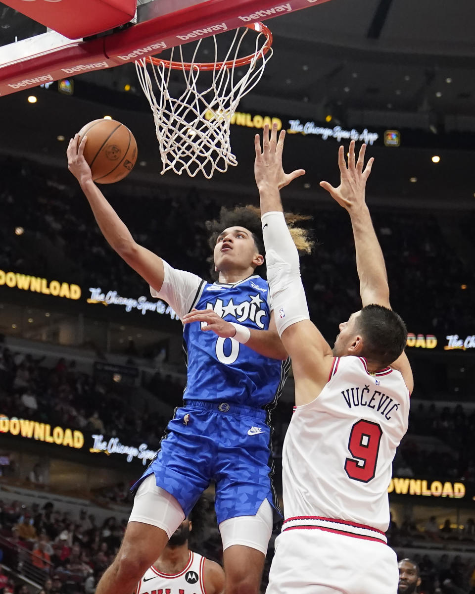 Orlando Magic's Anthony Black (0) drives to the basket past Chicago Bulls' Nikola Vucevic during the first half of an NBA basketball game Wednesday, Nov. 15, 2023, in Chicago. (AP Photo/Charles Rex Arbogast)