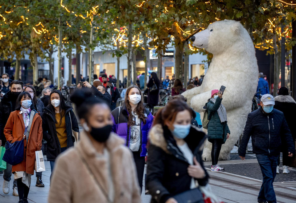 People walk in the main pedestrian zone in Frankfurt, Germany, Monday, Dec. 14, 2020. The German government is calling on citizens to forgo Christmas shopping two days before the country heads into a hard lockdown that will shut most stores, tighten social distancing rules and close schools across the country. (AP Photo/Michael Probst)