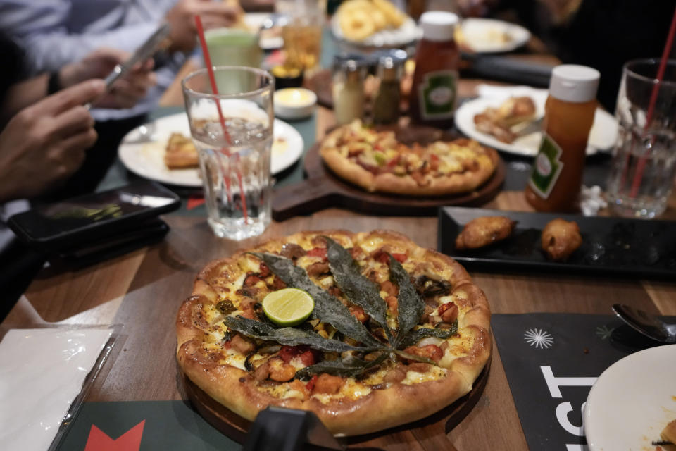 A pizza topped with a cannabis leaf is served to the customers at a restaurant in Bangkok, Thailand on Nov. 24, 2021. The Pizza Company, a Thai major fast food chain, has been promoting its "Crazy Happy Pizza" this month, an under-the-radar product topped with a cannabis leaf. It’s legal but won’t get you high. (AP Photo/Sakchai Lalit)