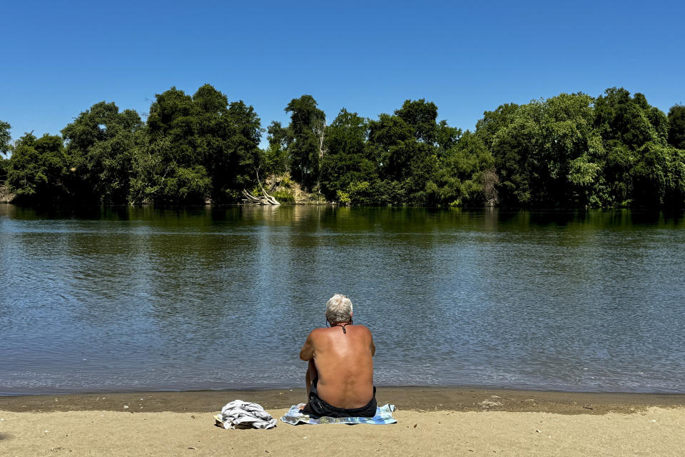 A man cools off by the river in Sacramento, Calif., Tuesday, July 2, 2024. Swaths of California sweltered Tuesday, and things were only expected to get worse during the Fourth of July holiday week for parts of the United States with nearly 90 million people under heat alerts. (AP Photo/Terry Chea)