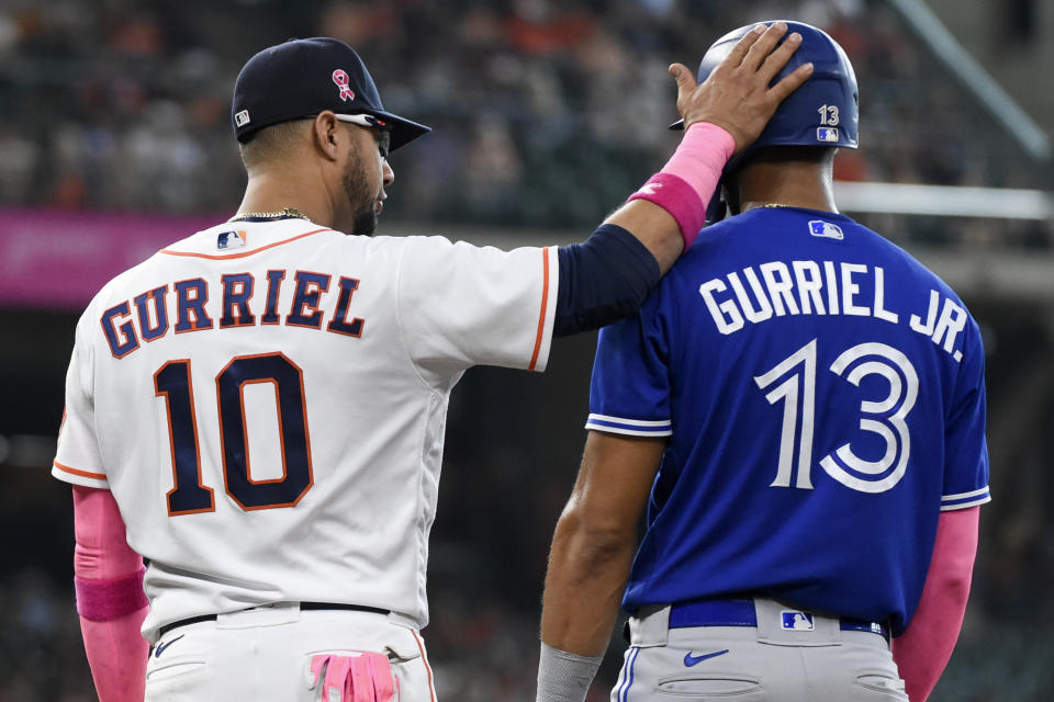 Houston Astros first baseman Yuli Gurriel (10) taps the helmet of his brother, Toronto Blue Jays' Lourdes Gurriel Jr., during the fifth inning of a baseball game, Sunday, May 9, 2021, in Houston. (AP Photo/Eric Christian Smith)