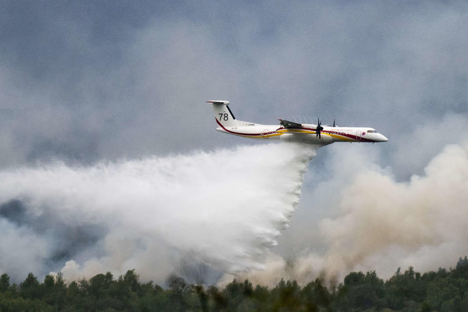 A De Havilland Canada Dash 8-400 MR aircraft drops water over a wildfire raging in the Monts d'Arree, near Brennilis, Brittany, on July 20, 2022. - A heatwave fuelling ferocious wildfires in Europe pushed temperatures in Britain over 40 degrees Celsius (104 degrees Fahrenheit) for the first time after regional heat records tumbled in France. (Photo by LOIC VENANCE / AFP)