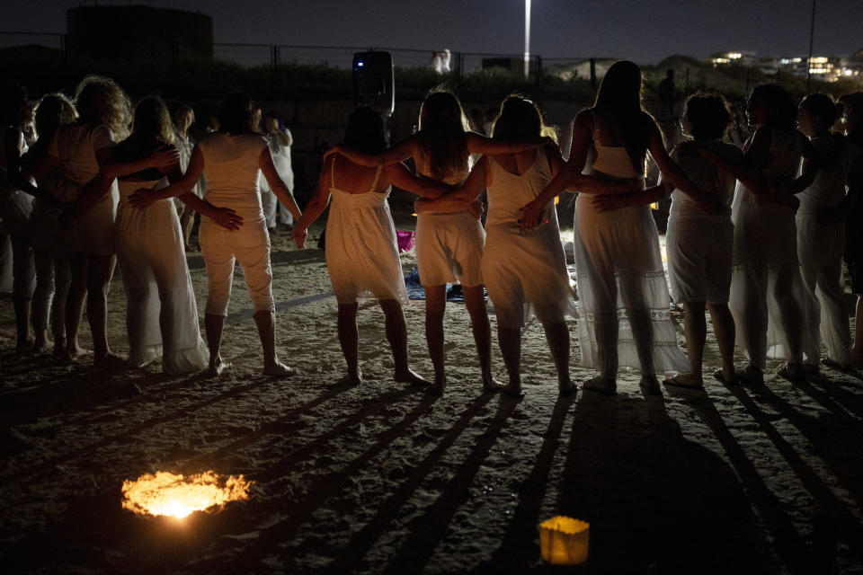 Women take part in a Tashlich ceremony, where they wrote down things they want to release before casting them into a fire, on the beach in Tel Aviv, Israel, Tuesday, Sept. 14, 2021. Tashlich, which means 'to cast away' in Hebrew, is the practice by which Jews go to a large flowing body of water and symbolically 'throw away' their sins by throwing a piece of bread, or similar food, into the water before the Jewish holiday of Yom Kippur, the holiest day in the Jewish year which starts at sundown Wednesday. (AP Photo/Maya Alleruzzo)