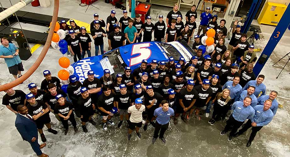 Group photo of Kyle Larson and auto tech students on the shop floor of the auto tech department at Hanahan (S.C.) High School