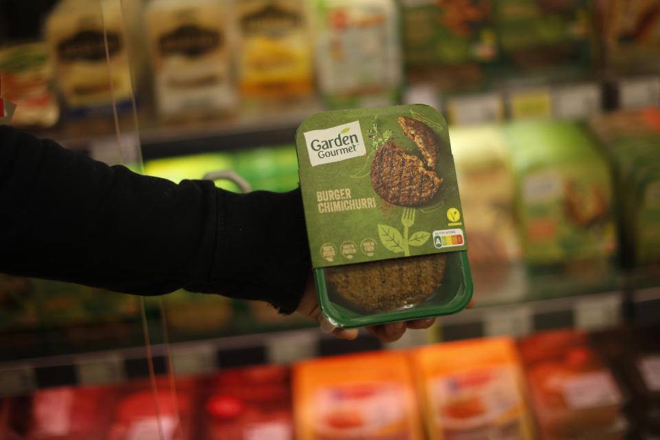 A store clerk shows a plant based burger at a supermarket chain in Brussels, Friday, Oct. 23, 2020. European lawmakers rejected Friday proposals that could have prevented plant-based products without meat from being labeled sausages or burgers. Following the votes on agricultural products at the European Parliament, the so-called veggie burgers, soy steaks and vegan sausages can continue to be sold as such in restaurants and shops across the union. (AP Photo/Francisco Seco)