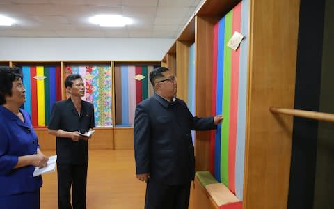 North Korean leader Kim Jong-un inspects some textiles while visiting the Sinuiju Textile Mill - Credit: AFP