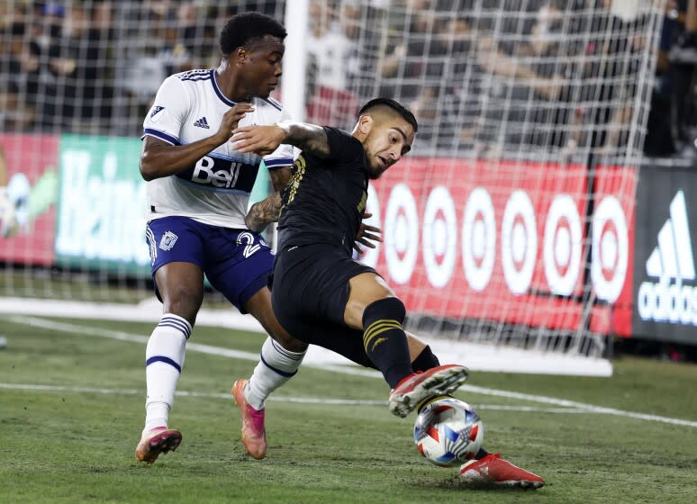 Los Angeles FC forward Cristian Arango, right, controls the ball while defended by Vancouver Whitecaps defender Javain Brown during the first half of an MLS soccer match Tuesday, Nov. 2, 2021, in Los Angeles. (AP Photo/Ringo H.W. Chiu)