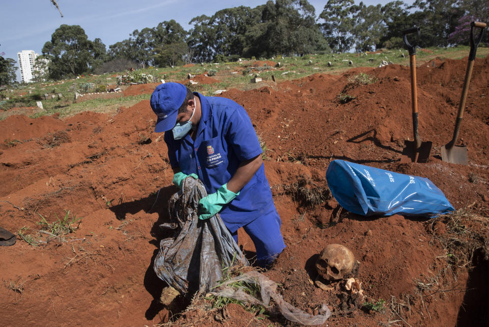 Un trabajador exhuma el cuerpo de una persona enterrada hace tres años en el cementerio de Vila Formosa, que no cobra a las familias por las tumbas, en Sao Paulo, Brasil, el 12 de junio de 2020. Los cuerpos sepultados hace al menos tres años, se exhuman y almacenan en bolsas de plástico para dejar sitio a más féretros, una necesidad más acuciante en la pandemia del coronavirus. (AP Foto/Andre Penner)