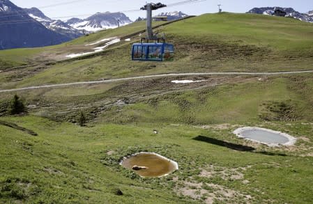 A cable car of the Weisshornbahnen is seen above as bear Napa enjoys a bath in a pond at the Arosa Baerenland sanctuary in the mountain resort of Arosa