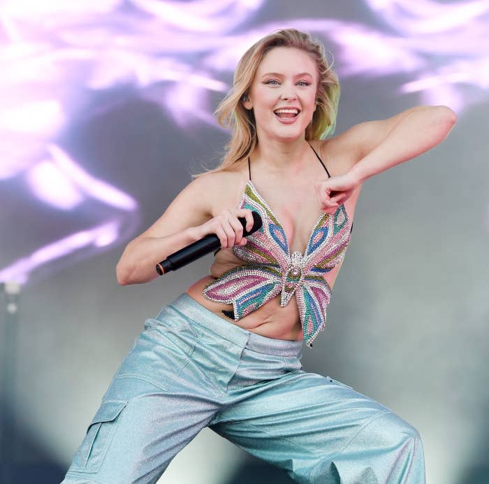 Zara dancing onstage as she performs in a butterfly top and pants