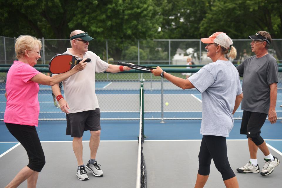 Roberta Atkins, from left, Joel Huber, Leon Waldschmidt and Ladawn Nesje hit paddles after their pickleball game at Riverdale Park Thursday, July 19, in Sioux Falls. Pickleball in the Park tournament will be held this upcoming weekend.