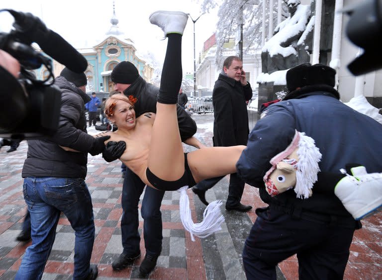 Police officers detain a Femen activist protesting in front of the Ukrainian parliament in Kiev on December 12, 2012. Activists from Ukraine's feminist group Femen staged a topless anti-corruption protest on Wednesday outside the ex-Soviet country's newly-elected parliament as a fight erupted between lawmakers inside