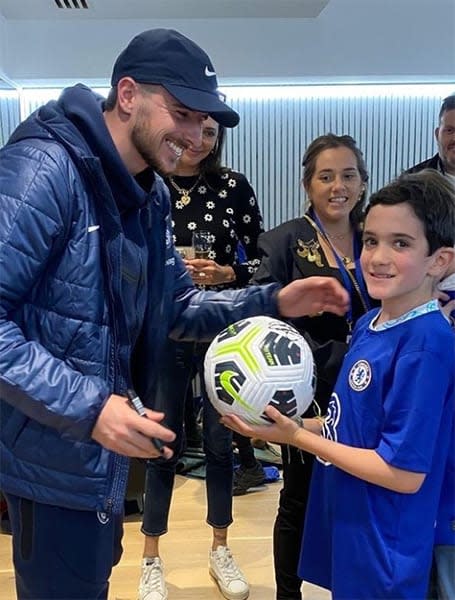 Mason Mount signing a football held by young boy