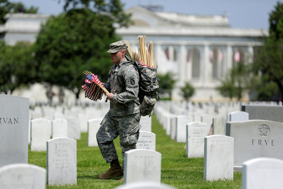 <p>A soldier of the 3rd U.S. Infantry Regiment (the Old Guard) carries flags before placing them in front of the graves at Arlington National Cemetery outside of Washington, D.C., May 26, 2016. (Reuters/Joshua Roberts) </p>