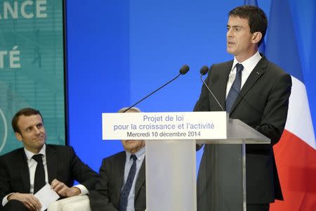 French Prime Minister Manuel Valls speaks (R) as Economy Minister Emmanuel Macron looks on during a press conference to present the "Law on Growth and Activity" plans, a package of measures aimed at stoking employment by freeing up some of France’s strict labour rules and regulations, at the Elysee Palace in Paris December 10, 2014. REUTERS/Lionel Bonaventure/Pool