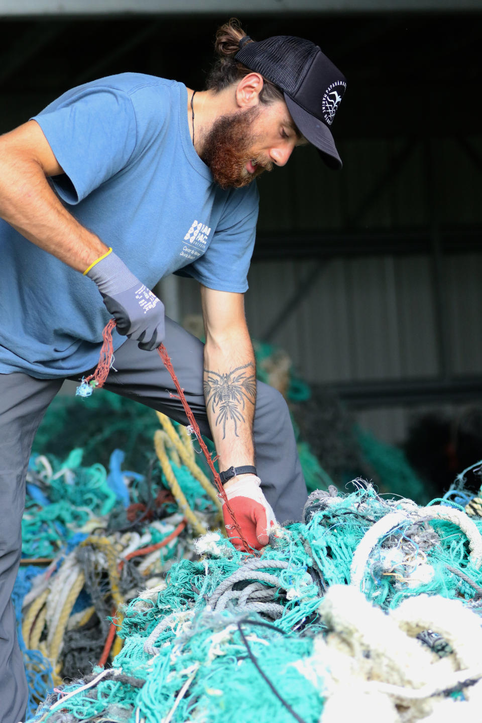 Drew McWhirter, a graduate student at Hawaii Pacific University's Center for Marine Debris Research, pulls apart a massive entanglement of ghost nets on Wednesday, May 12, 2021 in Kaneohe, Hawaii. Researchers are conducting a study that is attempting to trace derelict fishing gear that washes ashore in Hawaii back to the manufacturers and fisheries that it came from. (AP Photo/Caleb Jones)