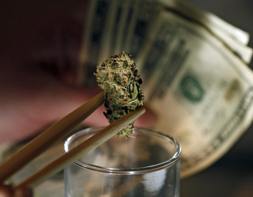 FILE -- In this Sept. 18, 2012 file photo a caregiver picks out a marijuana bud for a patient at a marijuana dispensary in Denver. On Wednesday, May 7, 2014, Colorado lawmakers approved an uninsured coop banking scheme, another step to institutionalize the cash-only marijuana industry. But it won't happen overnight. The Federal Reserve must approve services like credit cards and checking; the state must regulate any coop; the industry and/or banking sector must come up with trustworthy institutions to deliver these services. (AP Photo/Ed Andrieski, File)