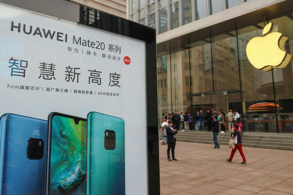 An advertisement for Huawei Mate 20 series is seen outside an Apple store, as customers queue before the store opens on the day the new iPhone XR goes on sale in Shanghai, China October 26, 2018. REUTERS/Stringer  ATTENTION EDITORS - THIS IMAGE WAS PROVIDED BY A THIRD PARTY. CHINA OUT.