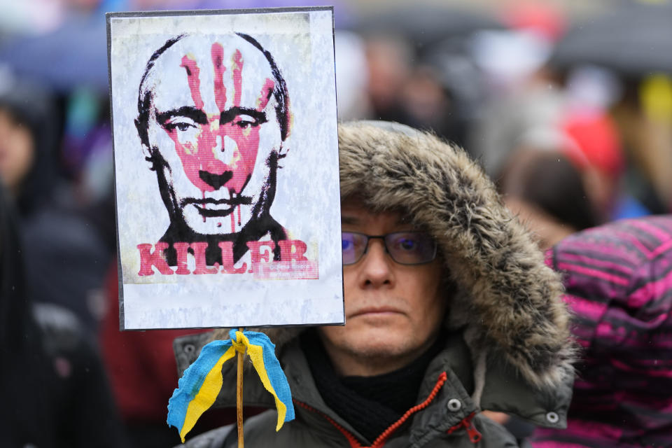 A demonstrator holds a placard of Russian President Vladimir Putin covered with a blood-smeared hand and a ribbon in the colors of the Ukraine flag during a rally in Budapest, Hungary, Saturday, April 2, 2022, ahead of Sunday's election. (AP Photo/Petr David Josek)