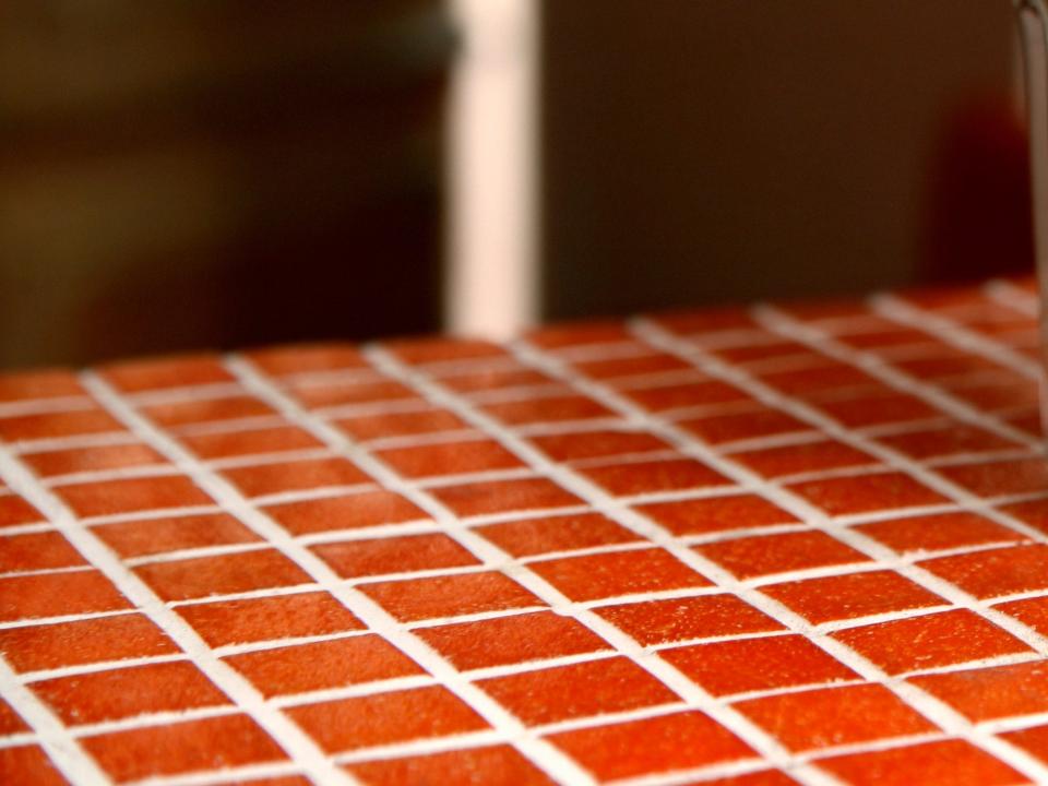 Red-orange tiled table with a glass of coffee on top