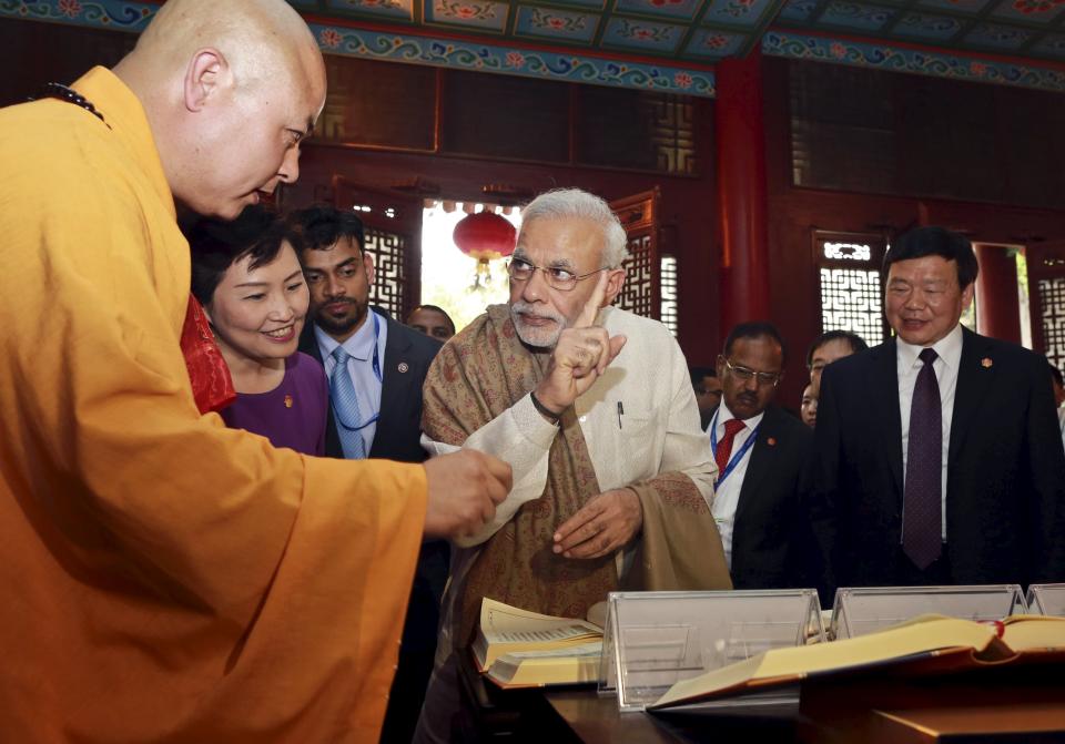 Indian Prime Minister Narendra Modi (C) gestures as he visits the Daxingshan Buddhist temple, in Xian