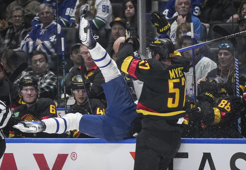 Vancouver Canucks' Tyler Myers, right, checks Toronto Maple Leafs' Calle Jarnkrok, left, into the Canucks' bench during the first period of an NHL hockey game in Vancouver, British Columbia, Saturday, Jan. 20, 2024. (Darryl Dyck/The Canadian Press via AP)