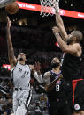 San Antonio Spurs' Dejounte Murray (5) shoots against Los Angeles Clippers' Marcus Morris, Sr. (8) and Nicolas Batum during the first half of an NBA basketball game, Saturday, Jan. 15, 2022, in San Antonio. (AP Photo/Darren Abate)