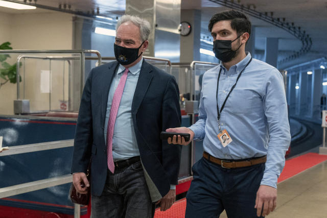 Sen. Tim Kaine, D-Va., left, talks to a reporter as he walks to the Senate Chamber for a vote, Wednesday, Dec. 15, 2021, in Washington. (AP Photo/Jacquelyn Martin)