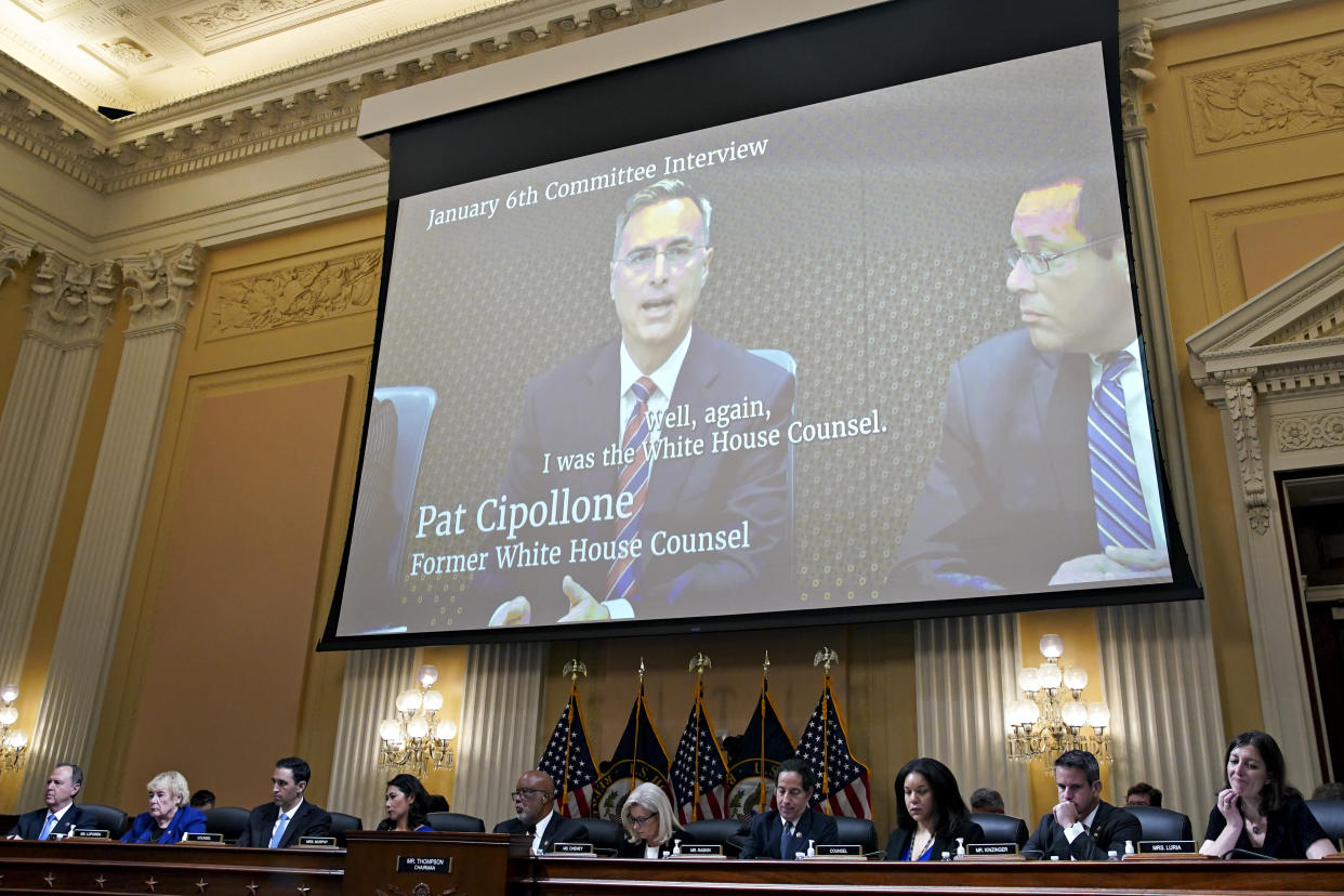 A video of Pat Cipollone is seen on a large screen above the heads of the January 6 committee members.