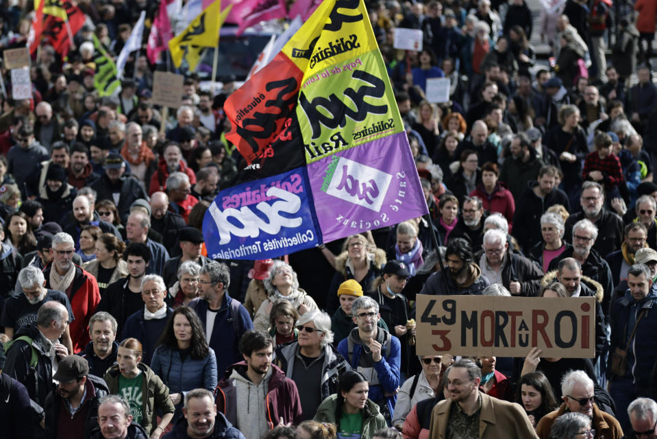 Protesters march one holding a placard reading '49.3, Death to the king' during a demonstration in Nantes, western France, Saturday, March 18, 2023. A spattering of protests are planned to continue in France over the weekend against President Emmanuel Macron's controversial pension reform. (AP Photo/Jeremias Gonzalez)