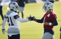 Dallas Cowboys quarterback Dak Prescott (4) greets teammate running back Ezekiel Elliott (21) at the beginning of an NFL football training camp practice in Frisco, Texas, Friday, Aug. 14, 2020. (AP Photo/LM Otero)