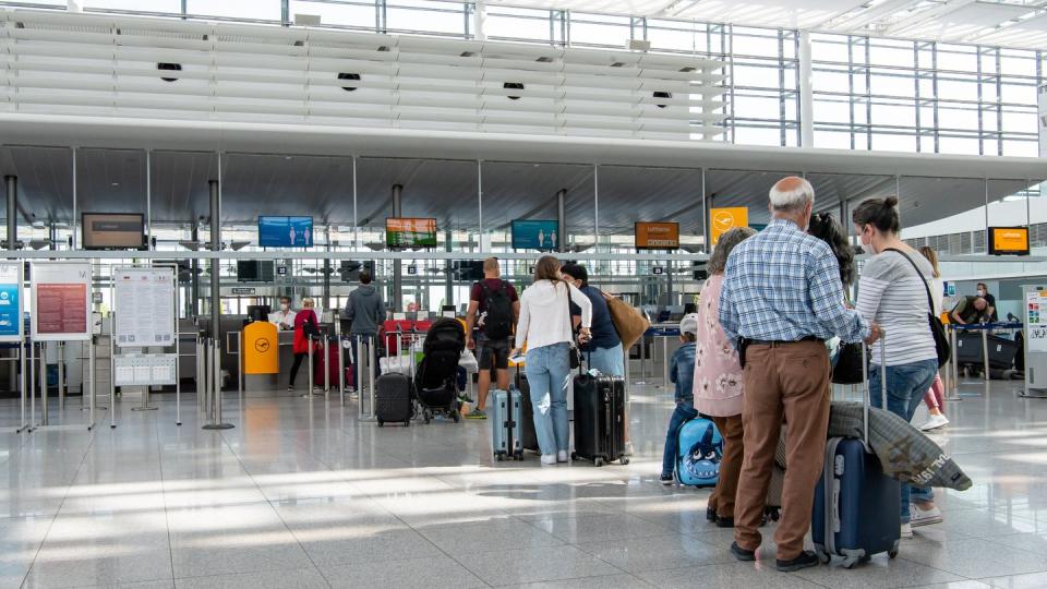 Fluggäste warten im fast leeren Terminal 2 des Münchener Flughafens auf den Check-In.