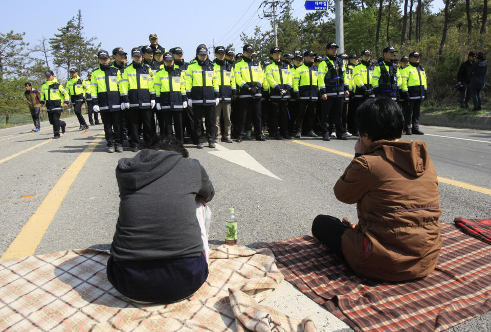 Relatives of missing passengers aboard the sunken ferry Sewol weep in front of policemen as they try to march toward the presidential house to protest the government's rescue operation in Jindo, South Korea, Sunday, April 20, 2014. After more than three days of frustration and failure, divers on Sunday finally found a way into the submerged ferry off South Korea’s southern shore, discovering more bodies inside the ship and one outside and pushing the confirmed death toll to over four dozen.  (AP Photo/Ahn Young-joon)