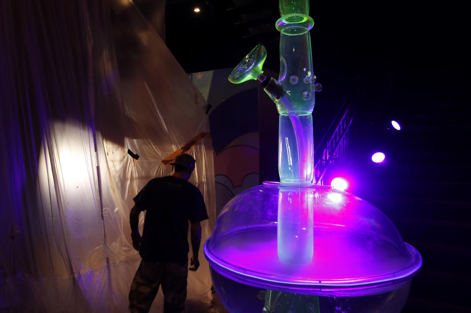 In this Tuesday, Sept. 18, 2018 photo, a man walks by a 24-foot-tall bong at the Cannabition cannabis museum in Las Vegas. The museum celebrating all things cannabis with displays that include a glass bong taller than a giraffe and huggable faux marijuana buds is the newest tourist attraction in Las Vegas. (AP Photo/John Locher)