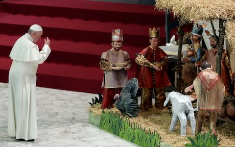 Pope Francis prays in front of a Nativity scene - Credit: Gregorio Borgia/AP