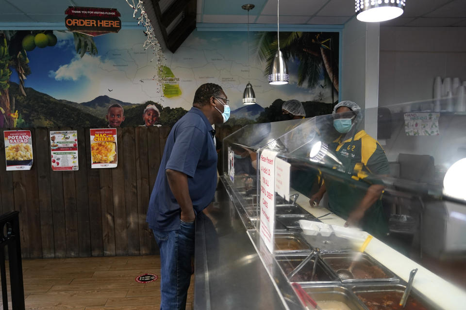 In this Aug. 26, 2020, photo a customer orders food at the Dutch Pot Jamaican Restaurant in Pembroke Pines, Fla. Voters in the Democratic stronghold of Broward County, which includes Pembroke Pines and Fort Lauderdale, are eager to defeat Trump, but say they are even more energized to turn out in support of California Sen. Kamala Harris, Biden’s running mate whose father is Jamaican. (AP Photo/Lynne Sladky)