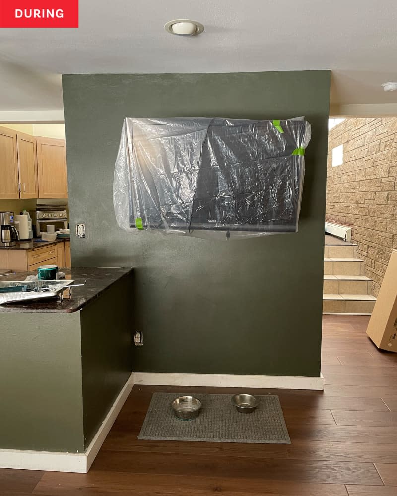 TV wall after diy makeover: Wall painted dark green with white trim, shelf added with plants. Art on walls around TV