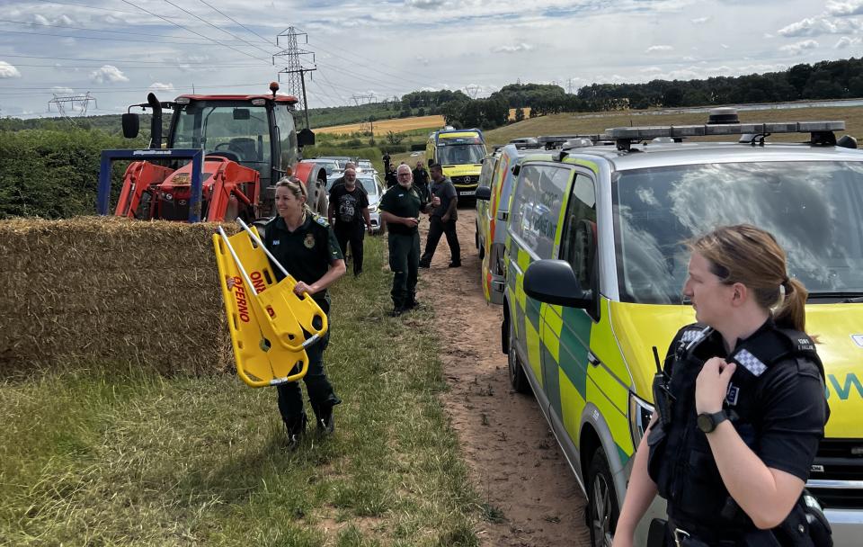 Rettungskräfte treffen vor Ort ein.  Siehe SWNS-Geschichte SWMRrescue.  Ein Bauer, der unter einem umgestürzten Heuballen eingeklemmt war, konnte gerettet werden, nachdem ein Einheimischer, der ihn um Hilfe schreien hörte, mithilfe einer App Rettungskräfte zum richtigen Feld leitete.  Der Softwareentwickler Michael Moss leckte gerade die Sonne vor seinem Haus in North Nottinghamshire, als er in der Ferne Hilferufe hörte.  Michael, gekleidet in Flip-Flops und mit einem Sandwich in der Hand, sprintete sofort in die allgemeine Richtung der Schreie, bis er auf einem Feld auf einen stillstehenden Traktor stieß.  Der zweifache Vater entdeckte Stephen, einen Bauern, der unter einem eine Tonne schweren Heuballen auf einem Feld eingeklemmt war und dessen Unterleib völlig zerquetscht war, und rannte ihm sofort zu Hilfe. 