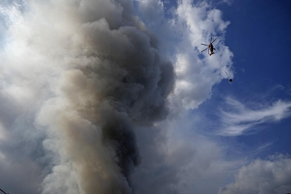 A helicopter extinguishes a fire at a warehouse of the online retailer Ozon in Istra Municipal District, northwest Moscow Region, Russia, Wednesday, Aug. 3, 2022. The fire, which erupted at the warehouse belonging to Russia's leading online retailer Ozon, has covered the area of 50,000 square meters and injured 11 people, two of whom were hospitalized. (AP Photo/Alexander Zemlianichenko)