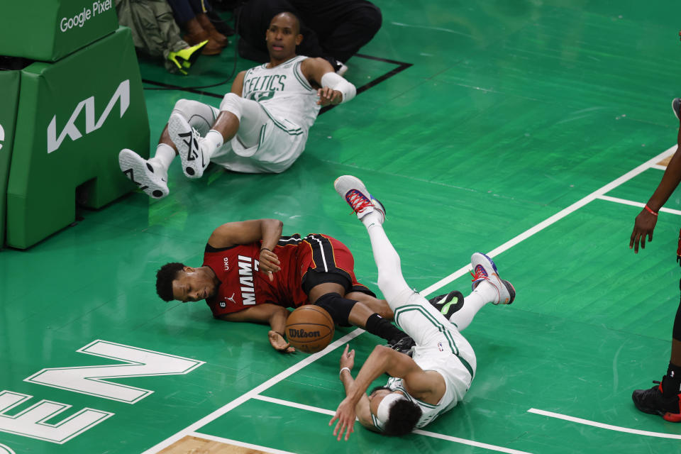Miami Heat guard Kyle Lowry (7) falls to the floor whale battling for the ball with Boston Celtics guard Derrick White, right, and center Al Horford in the second half of Game 1 of the NBA basketball Eastern Conference finals playoff series in Boston, Wednesday, May 17, 2023. (AP Photo/Michael Dwyer)