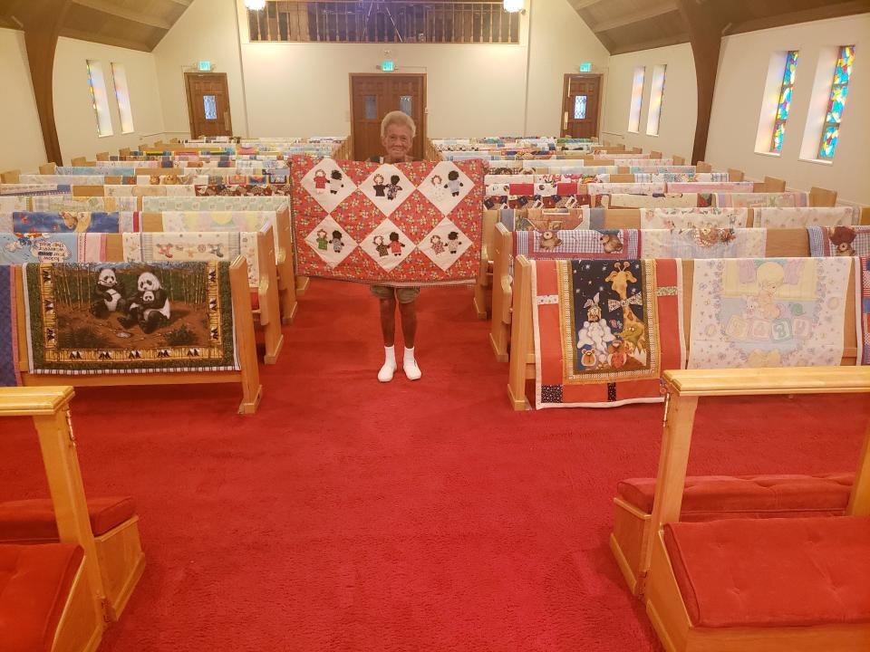 Donna Moyer, a member of St. Paul's Lutheran Church of Colon, holds up one of the 100 young children's quilts made by the Piecemakers Quilting Group which will be dedicated this Sunday at the church's 9:15 a.m. service.