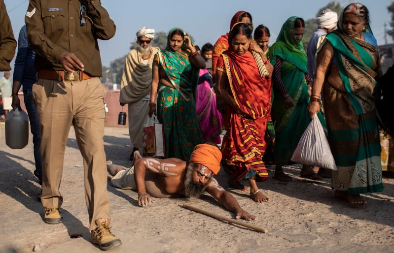 A Sadhu, or a Hindu holy man prostrates himself on a street as devotees and police officers walk past him after Supreme Court's verdict on a disputed religious site, in Ayodhya